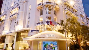 A tall, multi-story hotel with a grand entrance, large windows, and a prominent digital display. - Hotel Grand Saigon (Ho Chi Minh City)