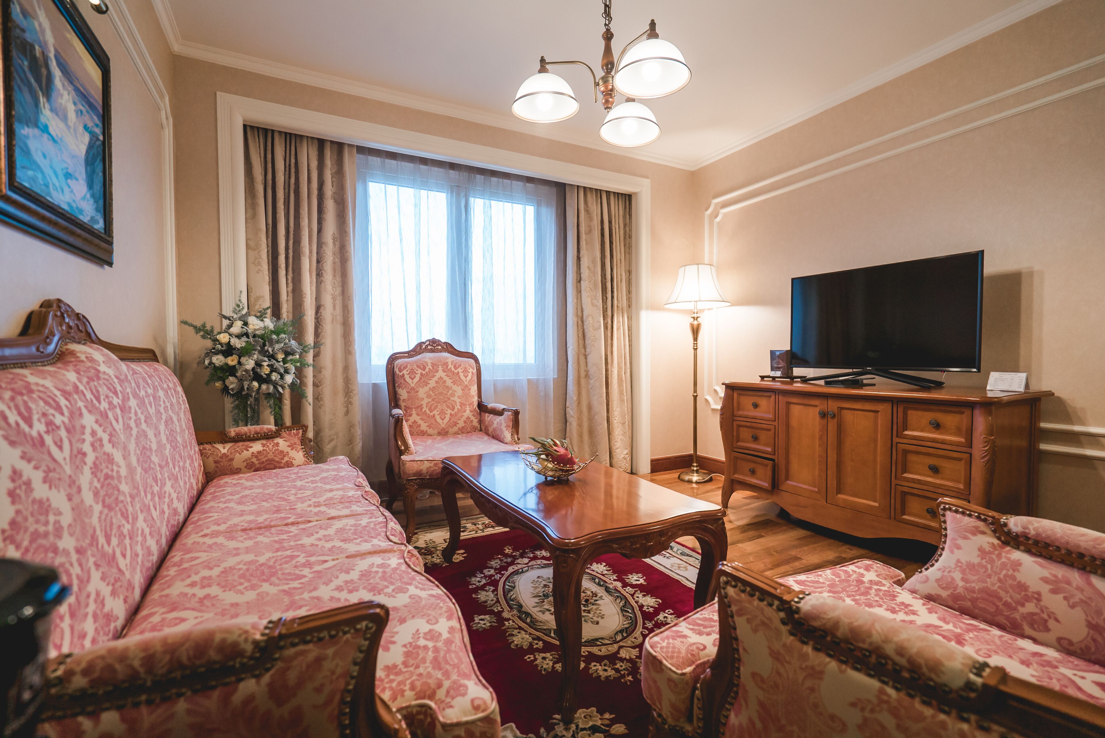A room with a sofa, a chair, a wooden table, a television, and a lamp.