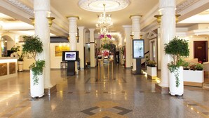 A spacious lobby with high ceilings, ornate columns, and a central chandelier. - Royal Hotel Saigon (Ho Chi Minh City)