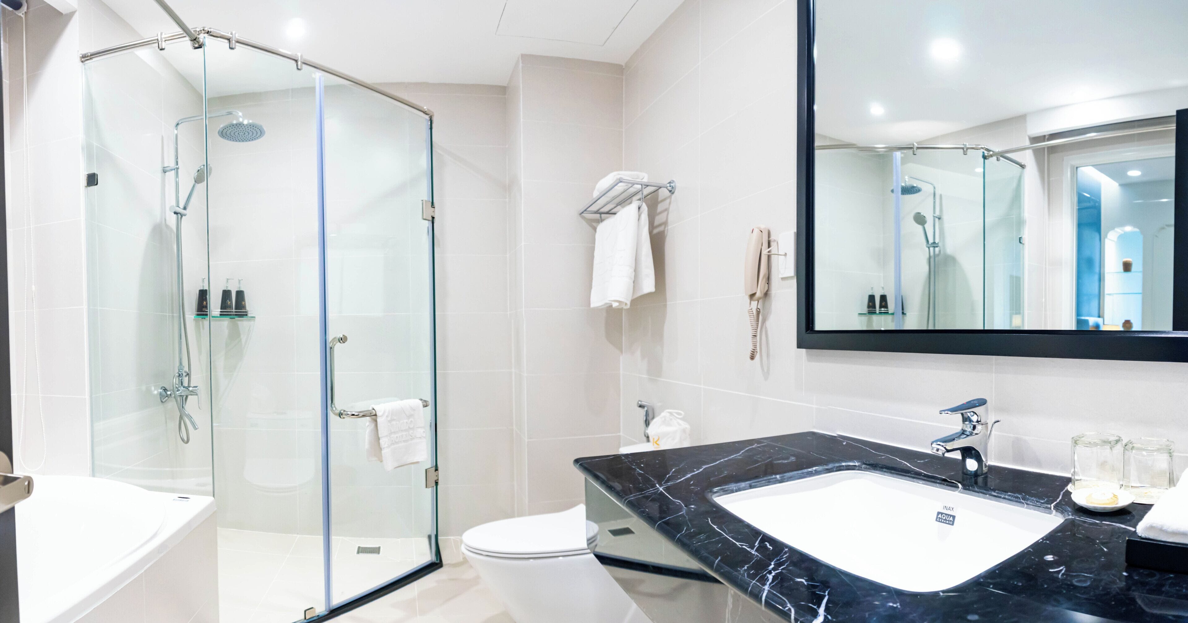 A modern bathroom with a glass-enclosed shower, a white toilet, and a black marble sink.