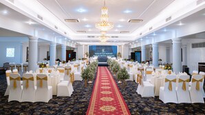 A banquet hall with white chairs, a red carpet, and a chandelier. - Royal Hotel Saigon (Ho Chi Minh City)