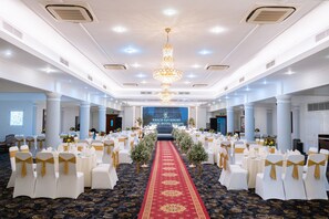 A banquet hall with white chairs, a red carpet, and a chandelier. - Royal Hotel Saigon (Ho Chi Minh City)