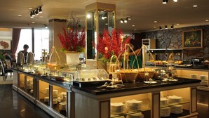 A buffet area with various food stations, glass display cases, and a central decorative plant arrangement. - Royal Hotel Saigon (Ho Chi Minh City)