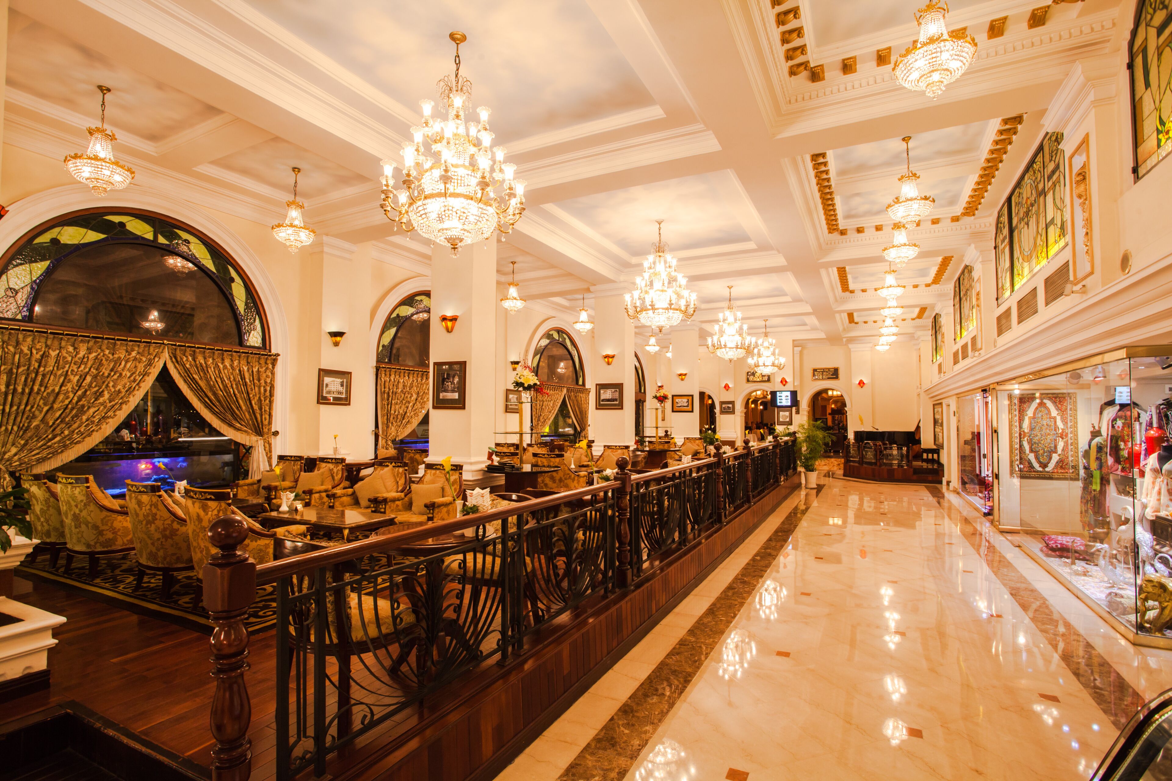 Un lobby de hotel imponente con candelabros, una larga recepción y vistas de la ciudad a través de amplios ventanales.