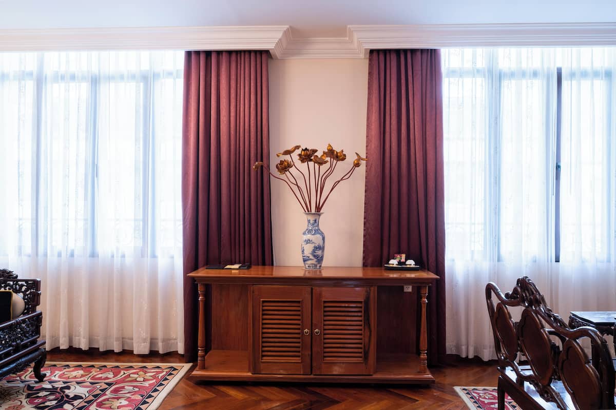 Ein Zimmer mit einem Holzschrank, einer Vase mit getrockneten Blumen und einem Essbereich mit Stühlen und einem Tisch.