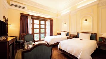 A hotel room with two beds, a desk, a chair, and a television.