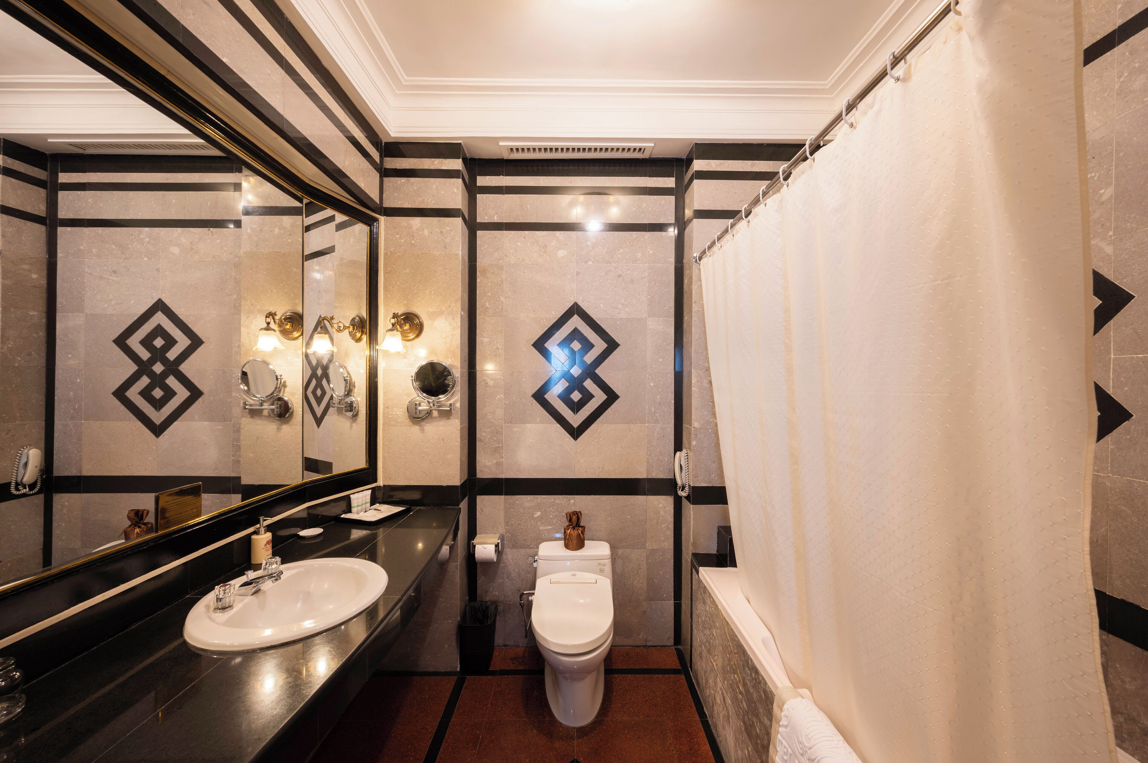 A modern bathroom with a large mirror, a sink, a toilet, and a shower curtain.