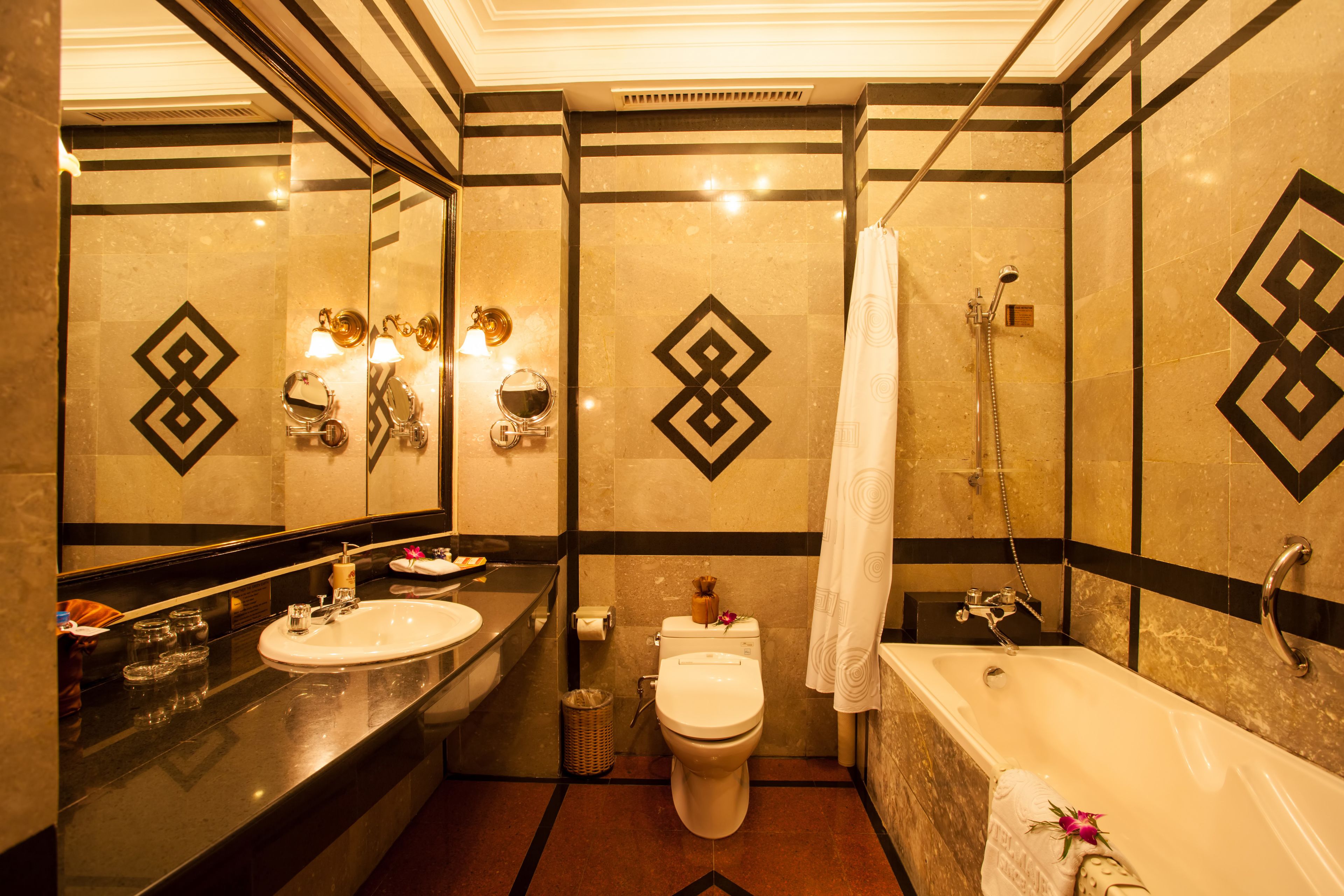 A modern bathroom with a large mirror, two sinks, a toilet, and a bathtub.