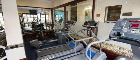 Un gimnasio con cintas de correr, bicicletas estáticas y equipamiento de ejercicio.