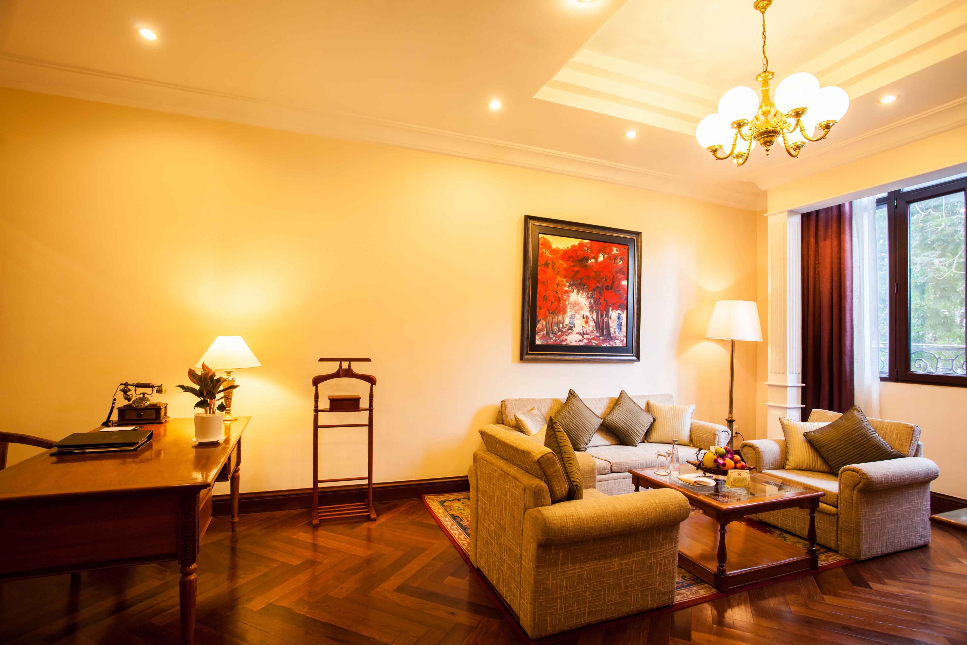 A living room with a sofa set, a coffee table, a lamp, and a painting on the wall.