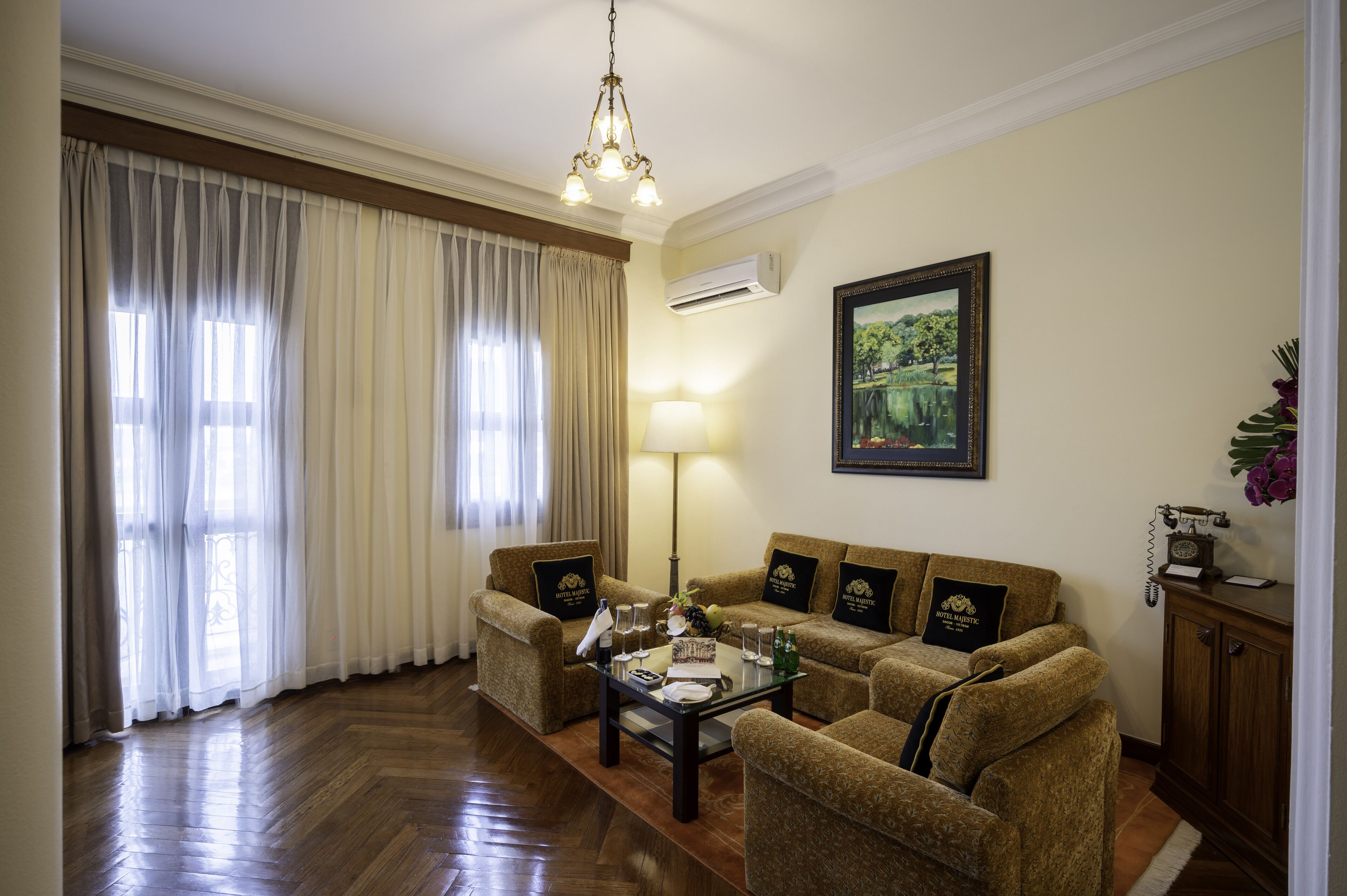 Un salón de hotel con un conjunto de sofás, una mesa de centro, una lámpara y un cuadro en la pared.