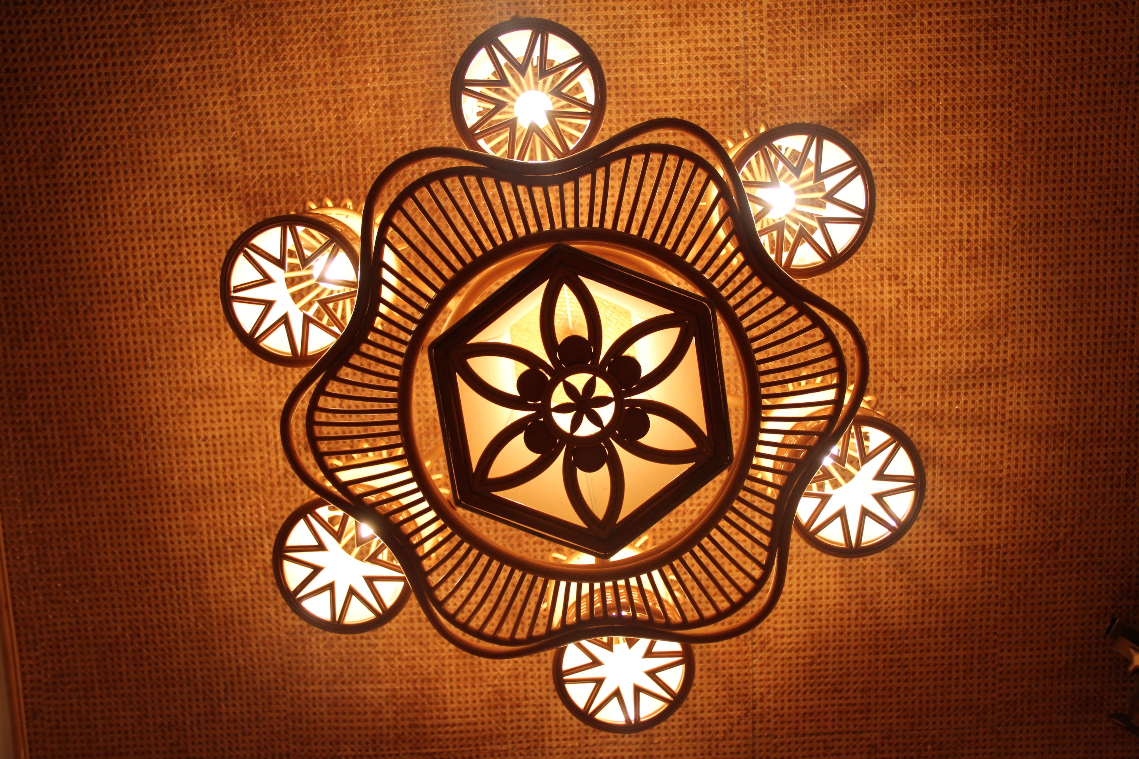 A decorative light fixture with a central floral design surrounded by circular elements.