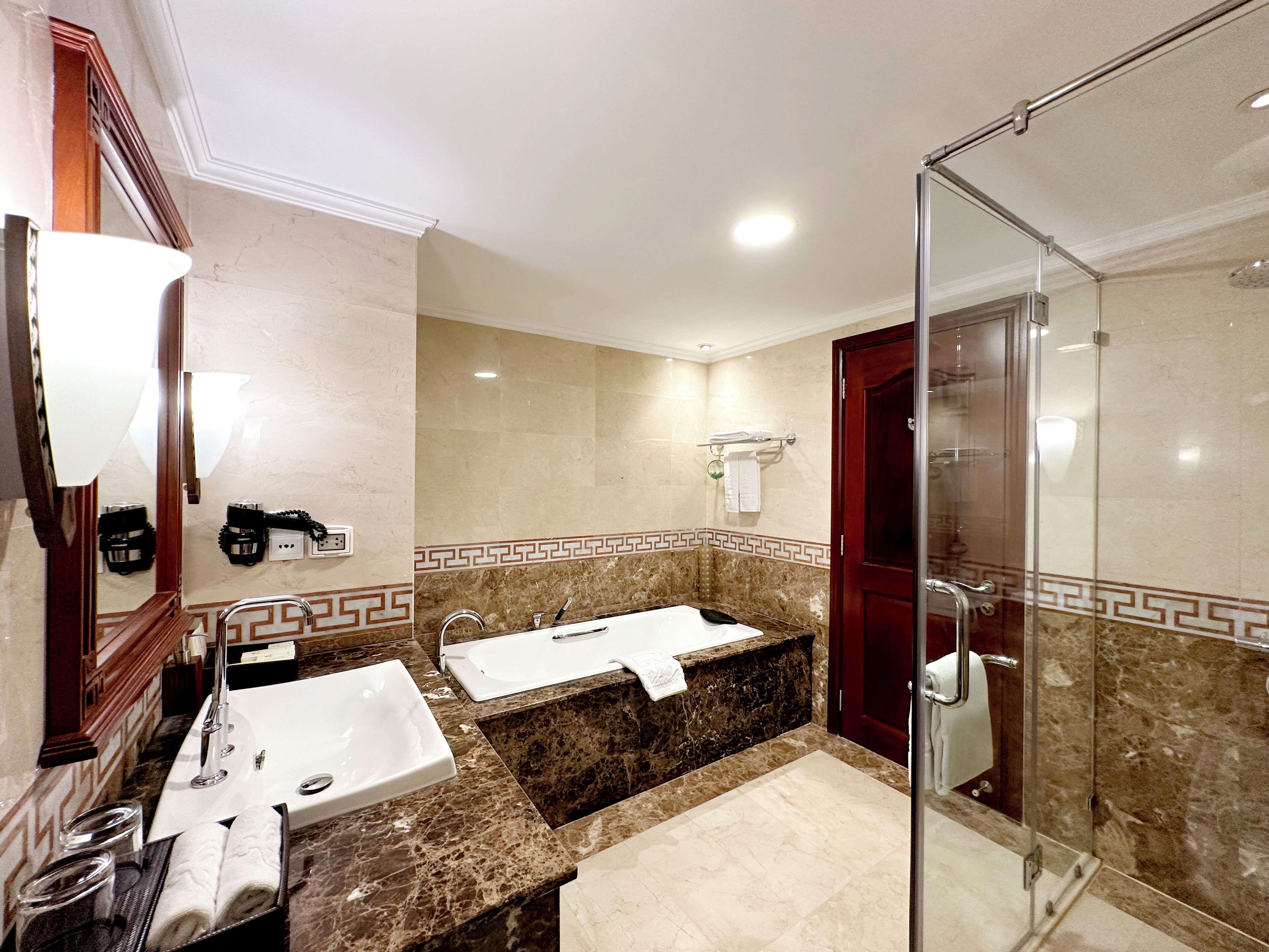 A bathroom with a double sink, a bathtub, and a glass-enclosed shower.