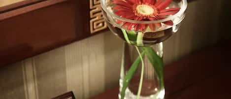 A framed sign with a message and a vase with a red flower on a wooden surface.