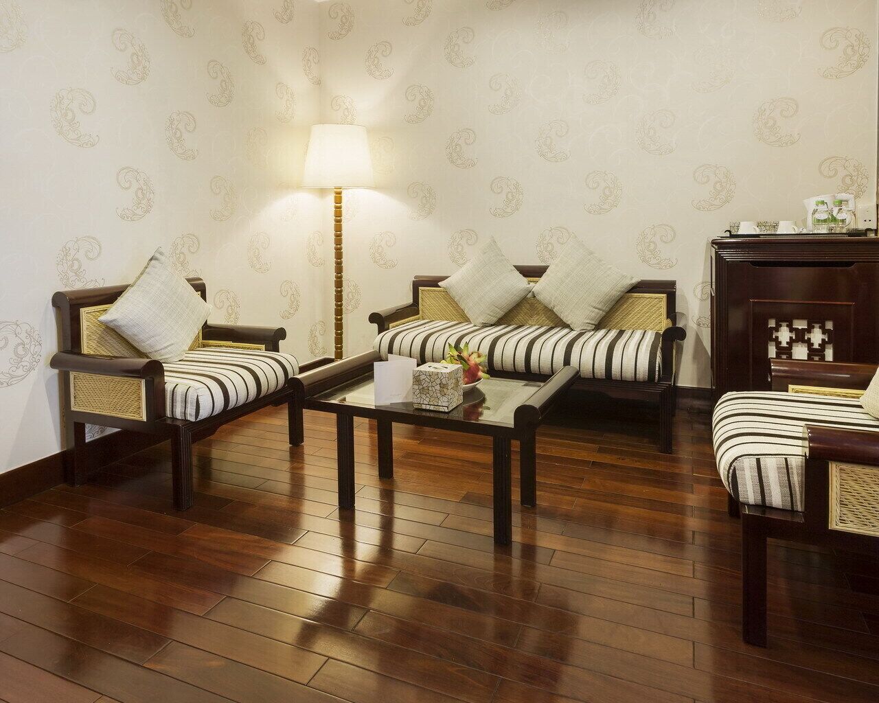 A traditional living room with two sofas, a coffee table, and a lamp.