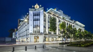 Un hotel moderno con un llamativo letrero del Hotel Rex, varios pisos y una tienda Chanel a nivel de calle.