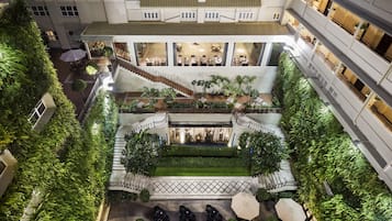 Experience the serene atmosphere of our hotel's multi-level atrium, featuring lush greenery and a central staircase.