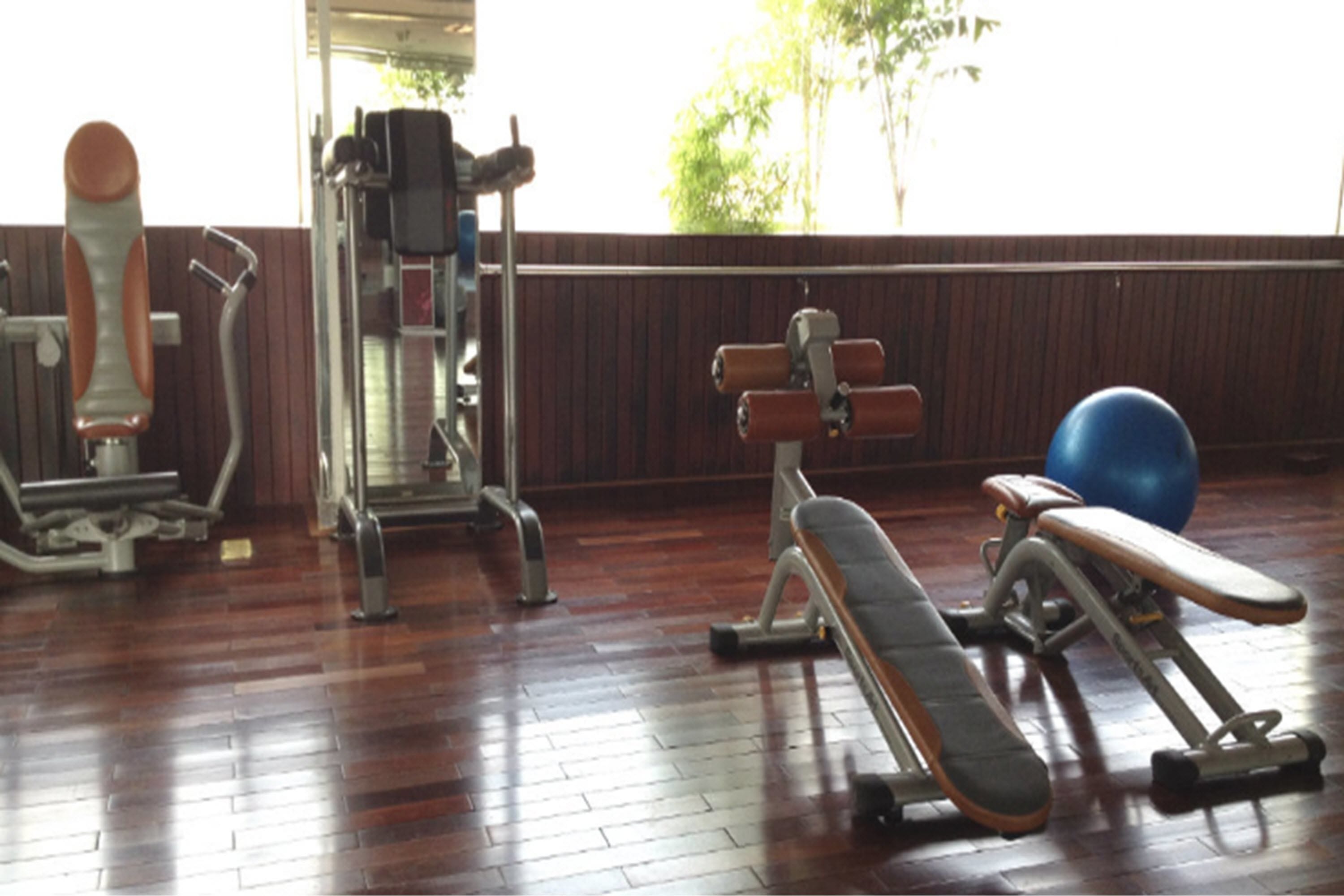 A gym with exercise equipment including a bench press, a leg press, and a blue exercise ball.
