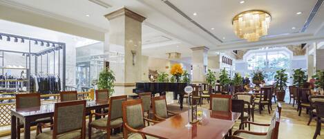 Un hall d’hôtel spacieux, agrémenté d’un magnifique lustre, de nombreuses tables et de fauteuils confortables.