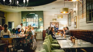 A restaurant with green upholstered booths, a bar area, and a dining area with tables and chairs. - The Castle at Taunton (Taunton)