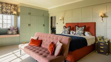 A bedroom with a large bed, a pink sofa, and a green wardrobe.