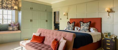 Une chambre avec un grand lit, un canapé rose et une armoire verte.