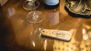 A wooden bar counter with a wine glass, a bottle of wine, and a wooden keychain with text.