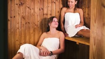 A wooden sauna with two people wrapped in towels.