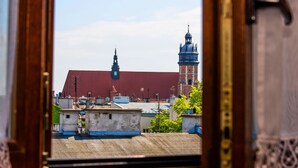 Vista a través de un marco de madera de un edificio con techo rojo y una torre de cúpula azul.
