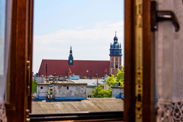A view through a wooden frame of a building with a red roof and a tower with a blue dome. - Hotel Kazimierz I (Kraków)