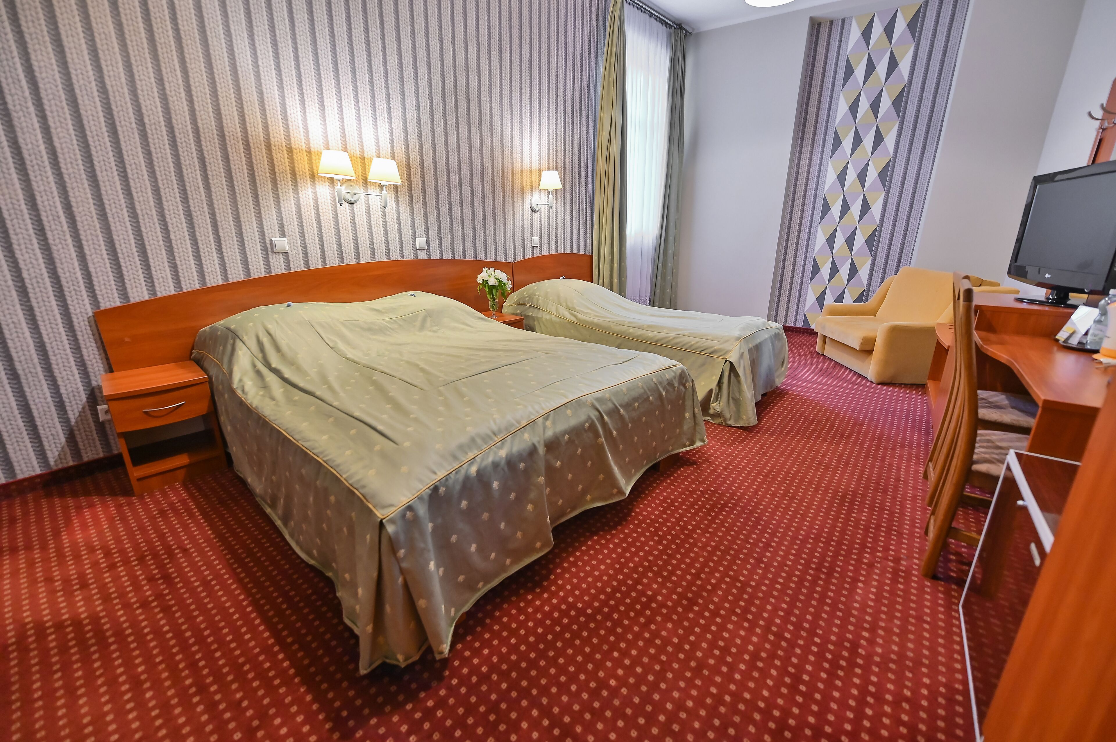Habitación de hotel con dos camas, un escritorio con computadora y televisor.