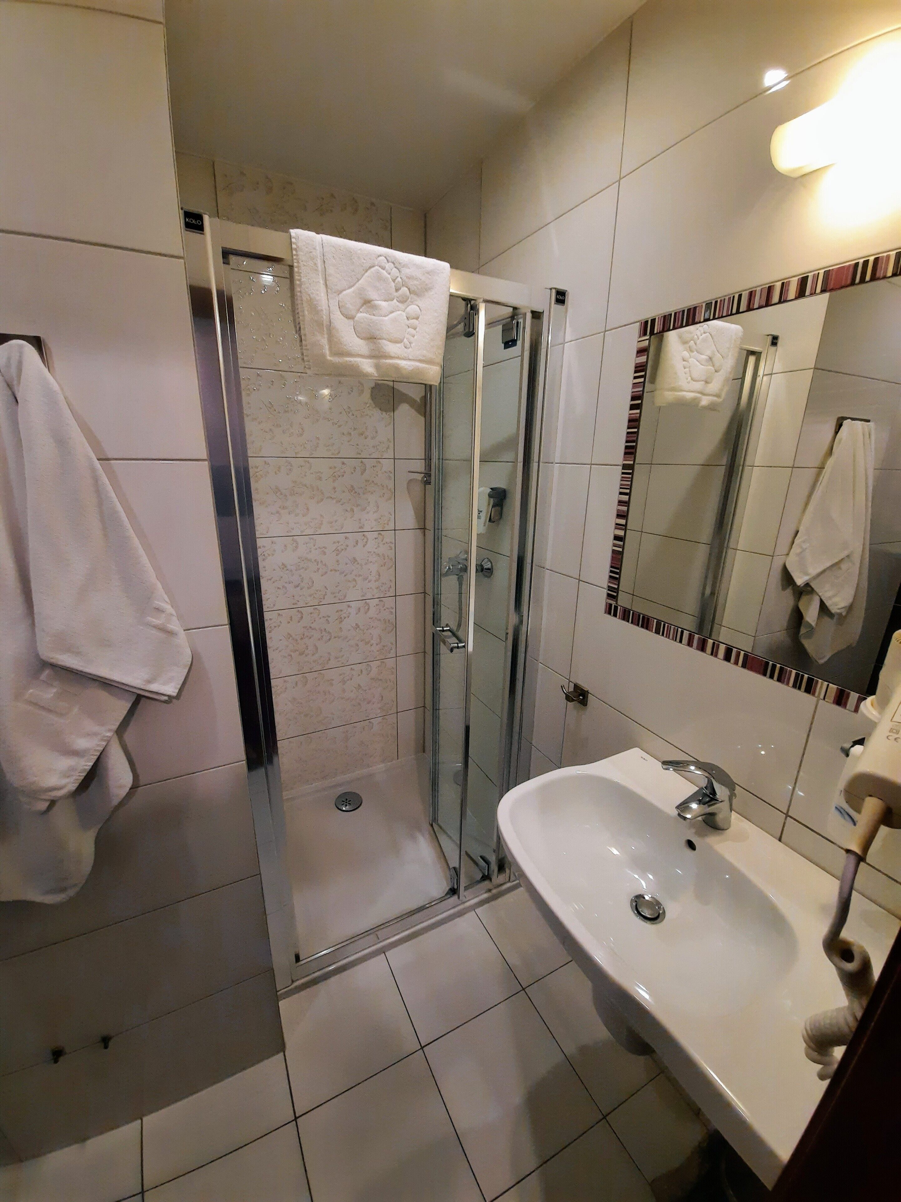 A modern bathroom with a glass-enclosed shower, a white sink, and a mirror with a striped border.
