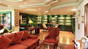 Un vestíbulo amplio con una zona de bar verde, asientos cómodos y un techo decorativo.