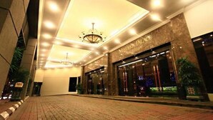 Entrada de un hotel con interior bien iluminado, un candelabro y un letrero que dice "MALIBU PLACE".