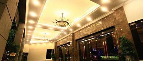 A hotel entrance with a well-lit interior, a chandelier, and a sign reading "MALIBU PLACE".