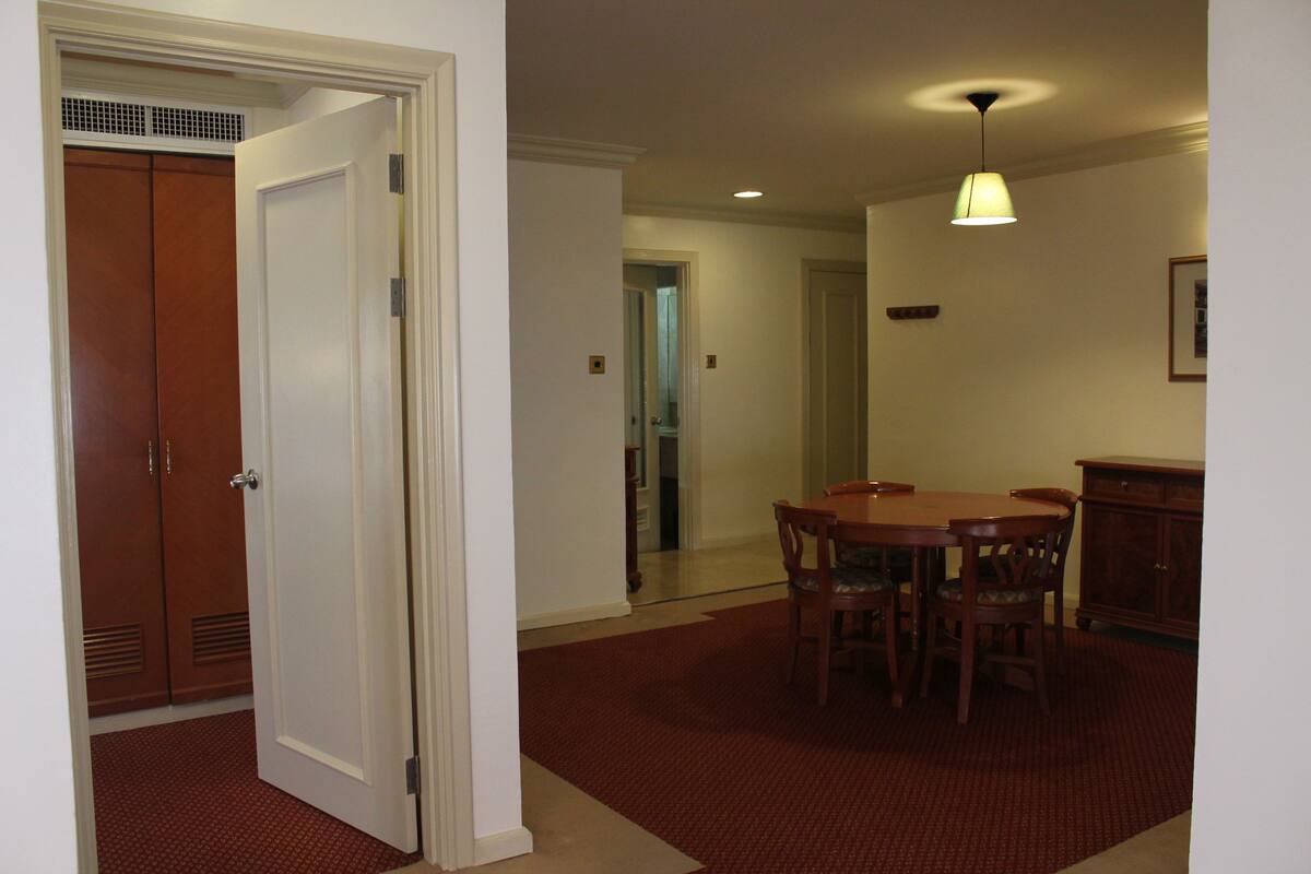 A room with a closed door, a dining table with chairs, and a cabinet.