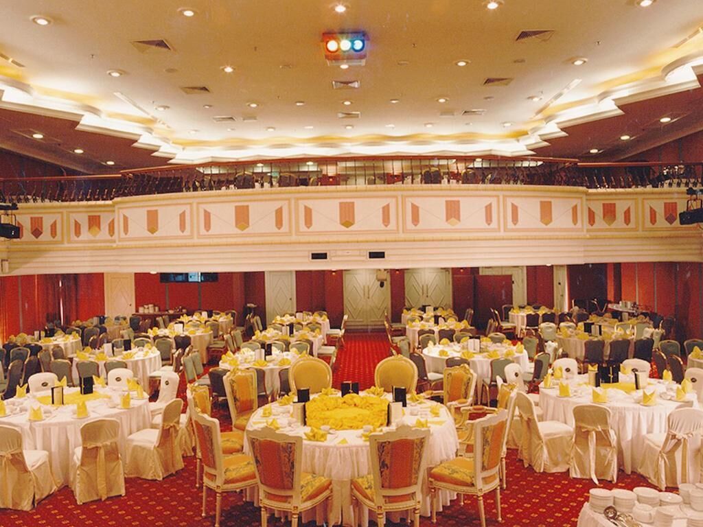 Une grande salle de banquet avec des tables rondes, des chaises et un balcon.