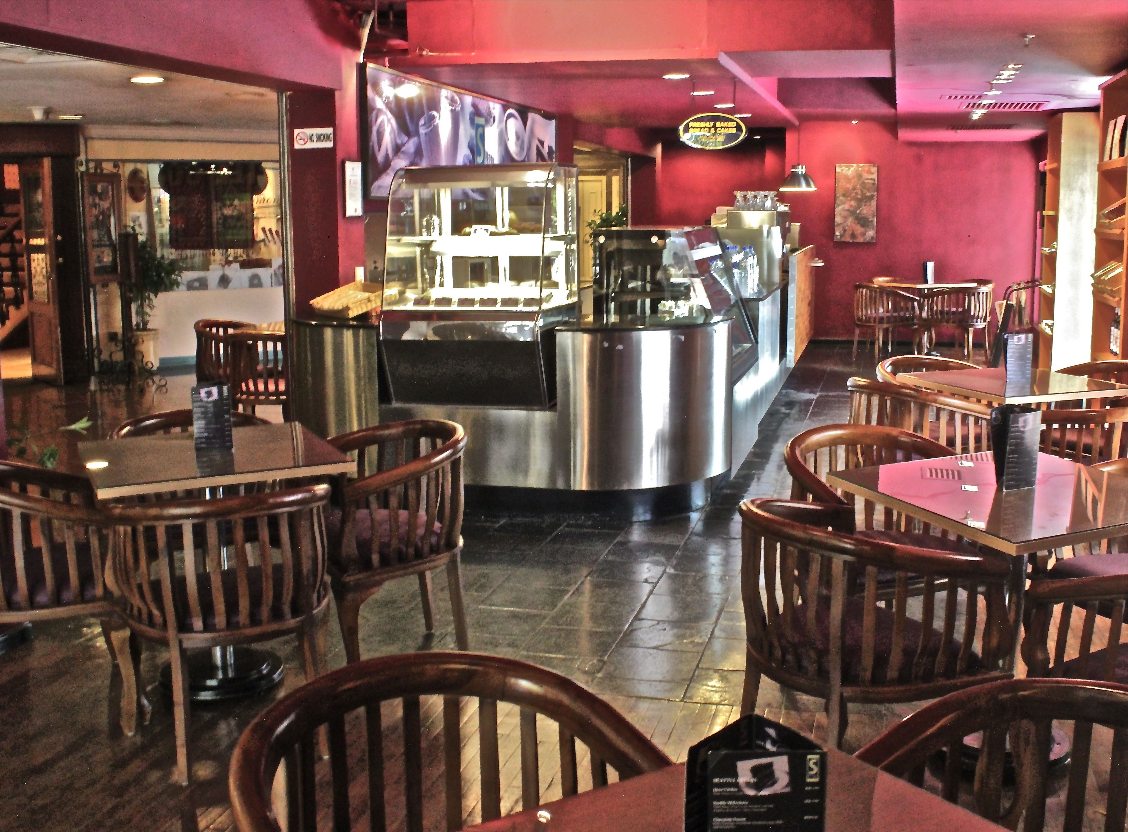 A restaurant interior with wooden chairs, a central counter, and a red wall.