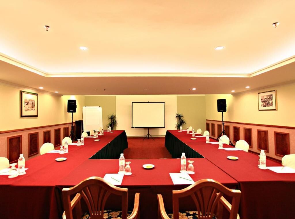 A conference room with a long table, chairs, a projector screen, and a whiteboard.