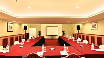 A conference room with a long table, chairs, a projector screen, and a whiteboard.