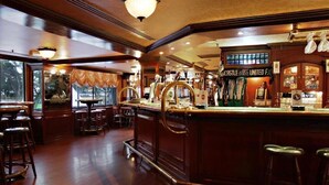 Una zona de bar con mostradores de madera, taburetes y un jukebox antiguo.