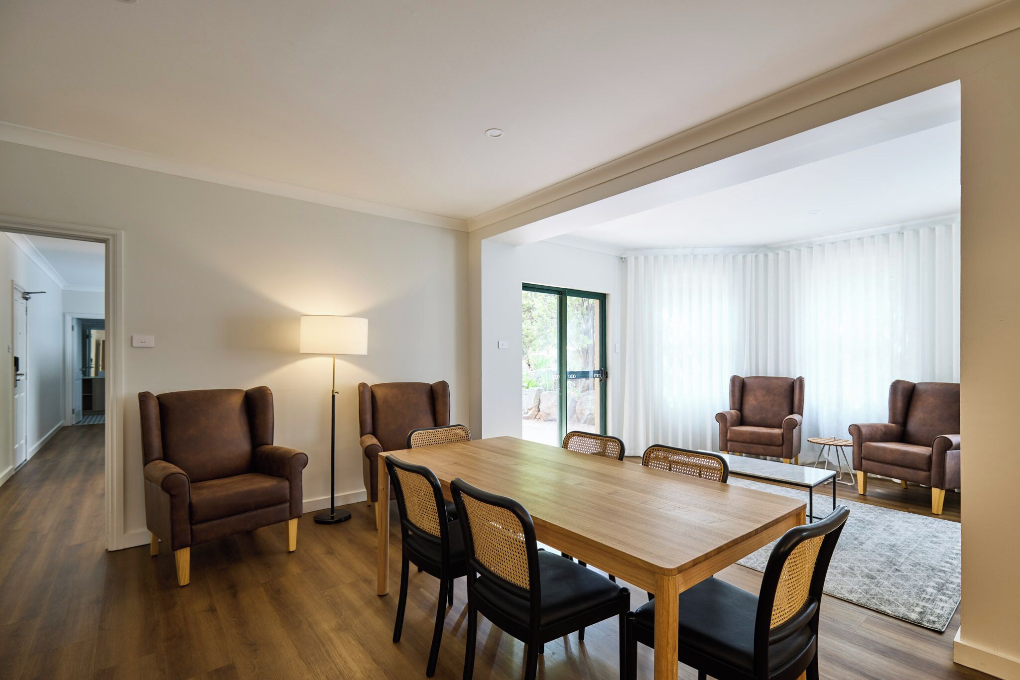 Une pièce spacieuse comprenant une table à manger en bois, quatre chaises, un lampadaire et deux canapés.