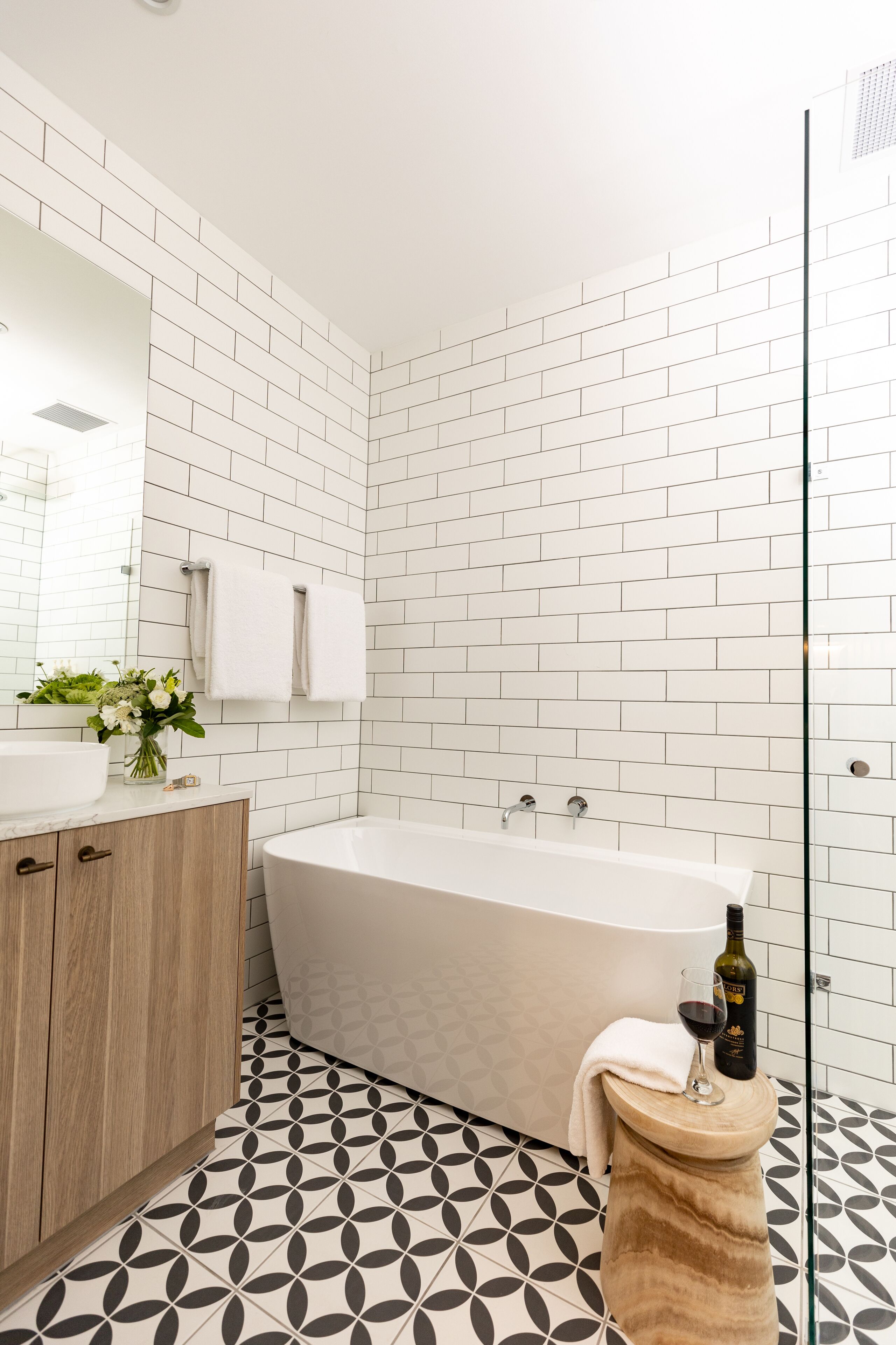 Ein modernes Badezimmer mit einer freistehenden Badewanne, einem Holzwaschtisch und einem Spiegel.