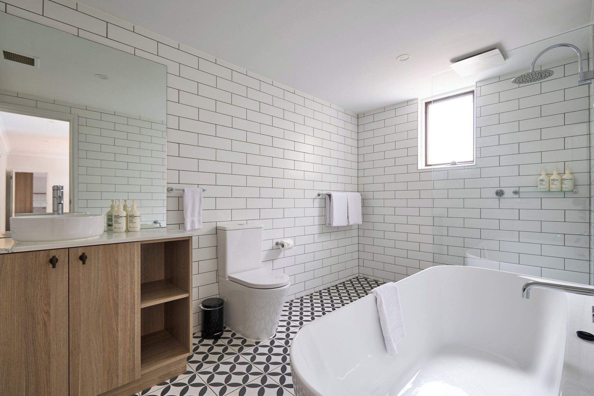 A modern bathroom with a white bathtub, a sink, a toilet, and a shower.