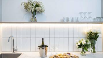 Una cocina moderna con un lavamanos integrado, una botella de vino en un cubo, una tabla de quesos y flores decorativas.