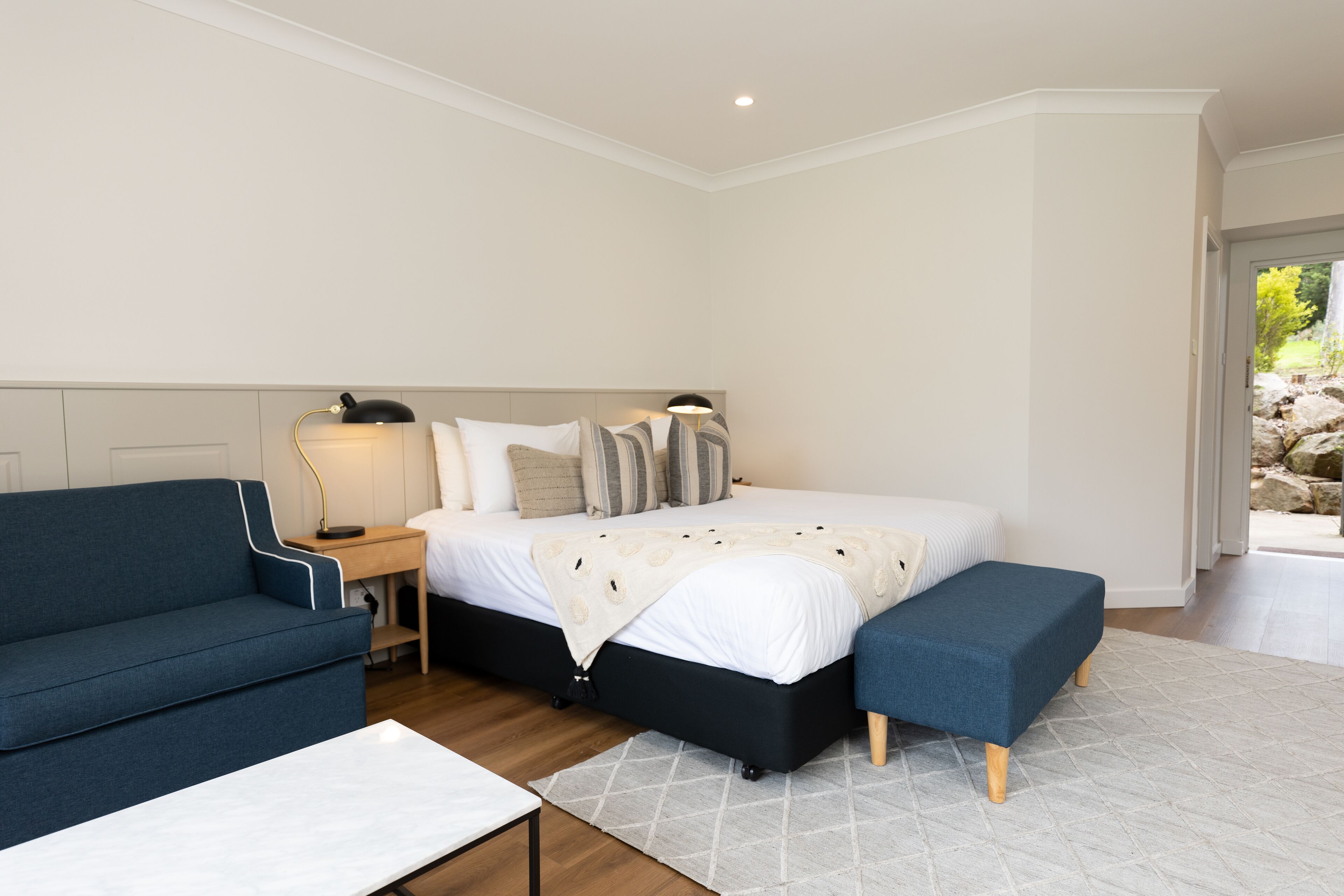 Un dormitorio con una cama, un sofá azul, una mesita de noche y una lámpara.