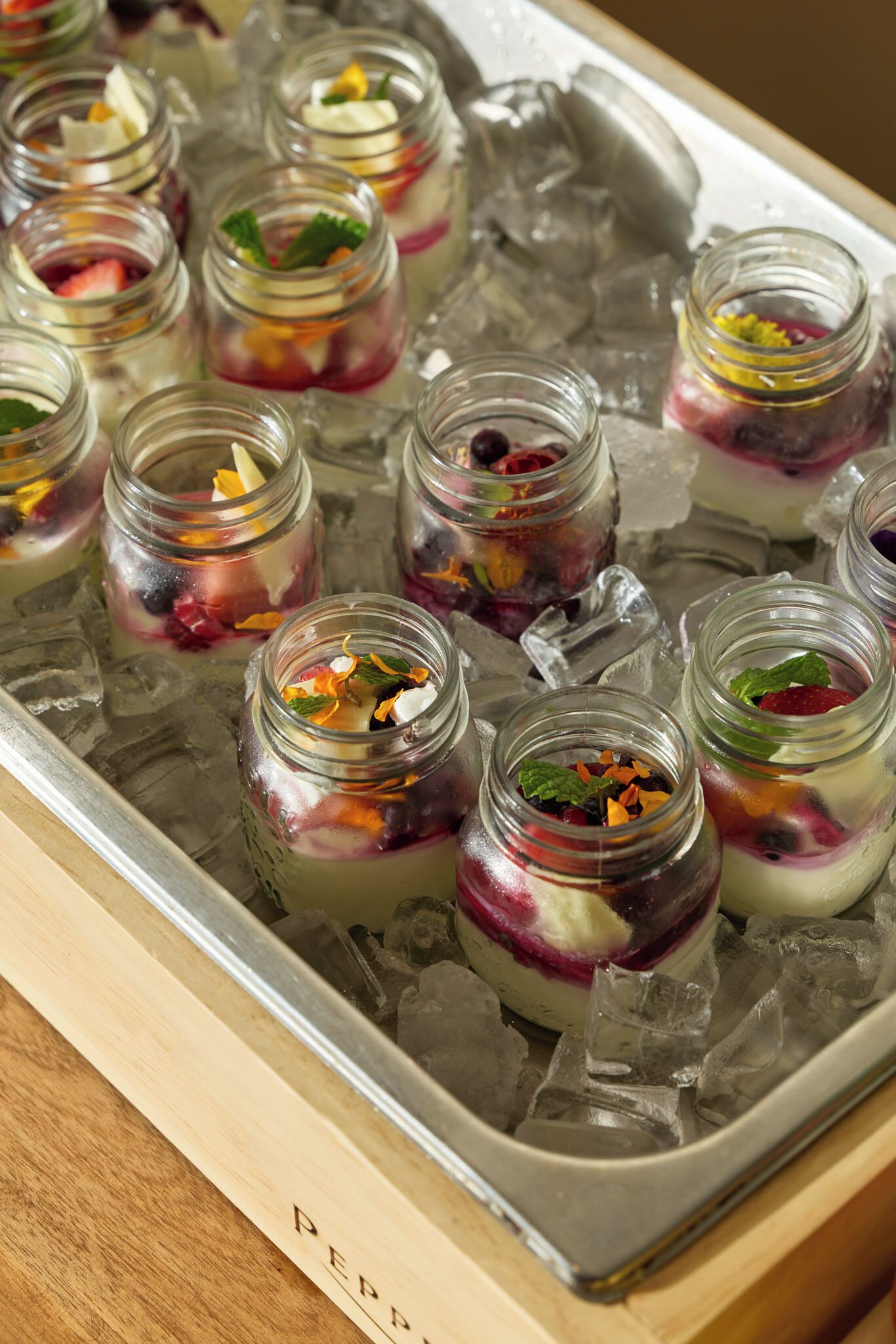 A tray of small jars with layered desserts on ice.