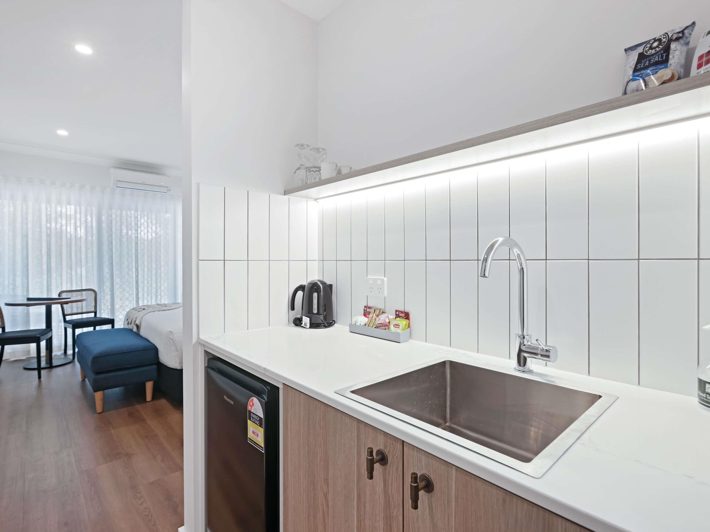 A modern kitchen with a sink, kettle, and storage cabinets.