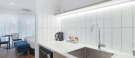 A modern kitchen with a sink, kettle, and storage cabinets.