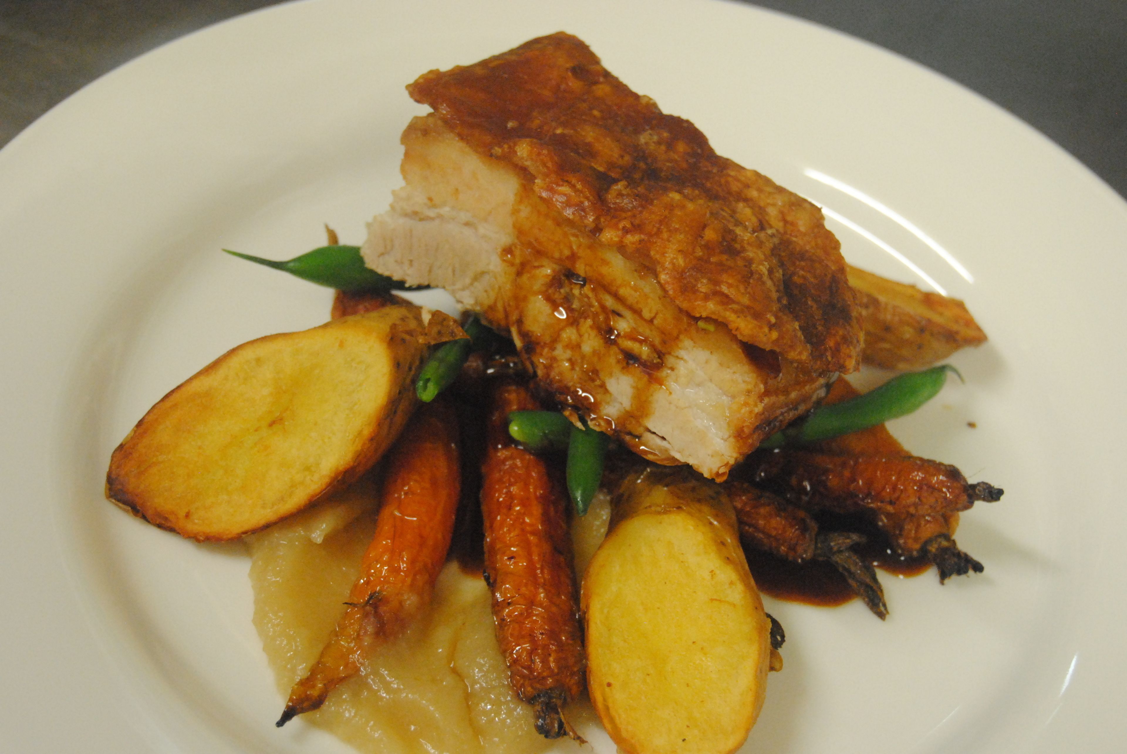 A plate of food with a piece of meat, potatoes, and carrots.